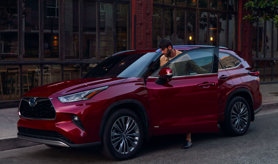 2023 Red Toyota Highlander parked on side of the road while man enters driver door