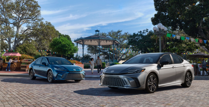 Two 2025 Toyota Camry cars parked on a sidewalk in front of a park