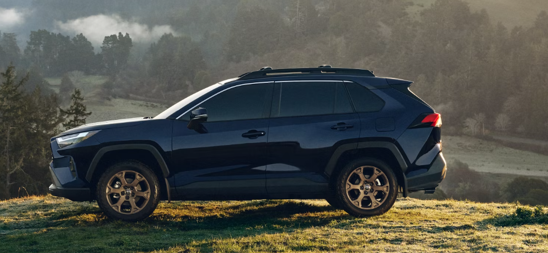 A black 2024 Toyota RAV4 Hybrid parked on a hillside at dawn