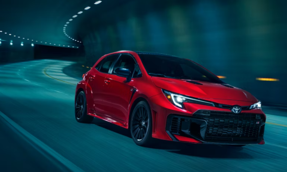 A red 2025 Toyota GR Corolla rounds a curve in a highway tunnel