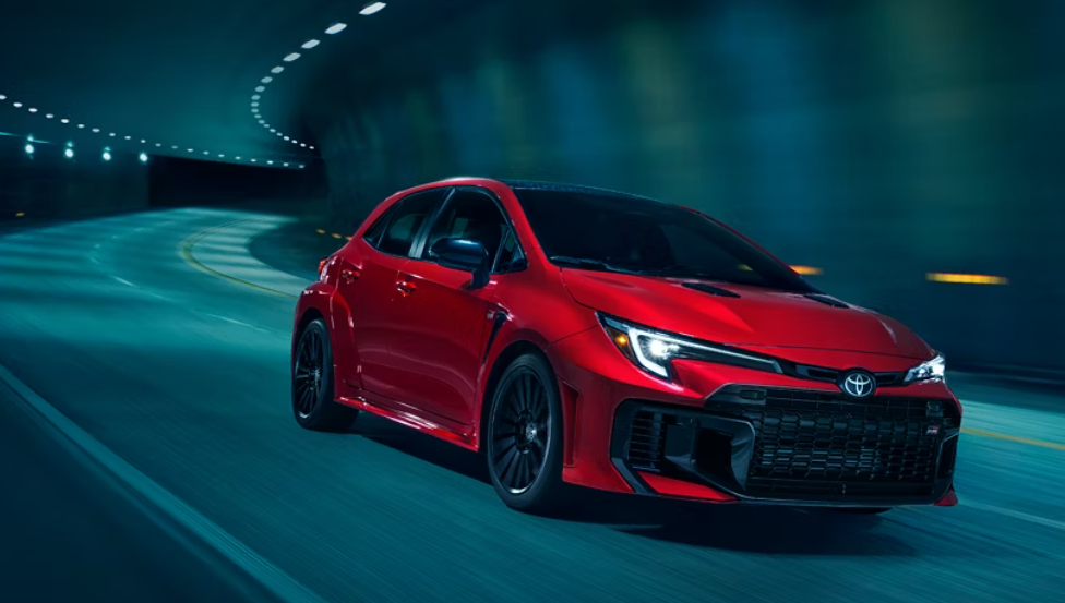 A red 2025 Toyota GR Corolla rounds a curve in a highway tunnel