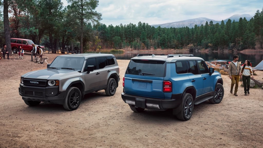 Two 2025 Toyota Land Cruisers parked at a lakeside campsite